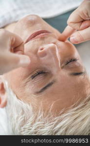 Marma therapy.  Beautiful senior woman lying on massage table and enjoying Ayurveda Facial treatment. . Marma Therapy. Ayurveda Facial Massage