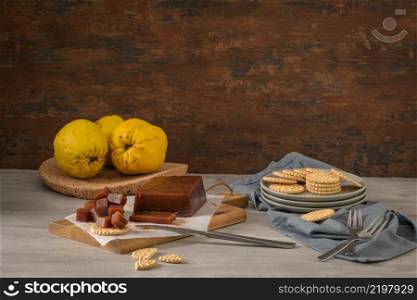 Marmalade in crackers on a kitchen counter with quinces on a cork tray.