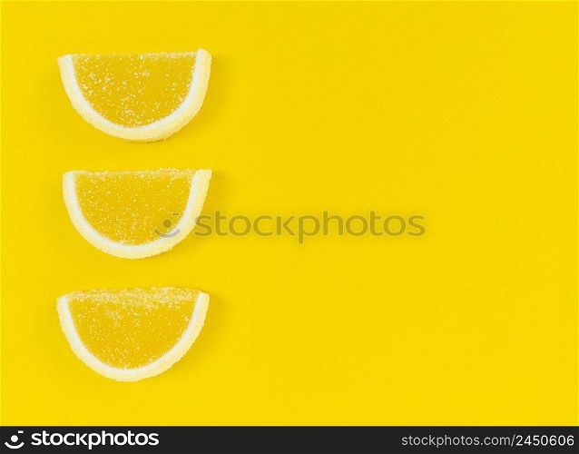 Marmalade lemon slices in sugar on a yellow background with copy space.. Marmalade lemon slices in sugar on yellow background with copy space.