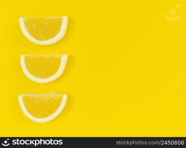 Marmalade lemon slices in sugar on a yellow background with copy space.. Marmalade lemon slices in sugar on yellow background with copy space.