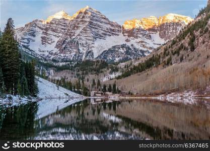 Maroon Bells and Maroon Lake with reflection of rocks and mountains in snow at sunrise around at autumn in Colorado, USA.