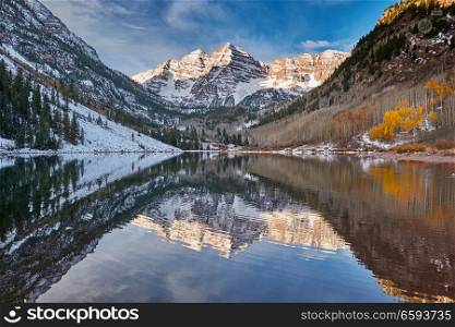 Maroon Bells and Maroon Lake with reflection of rocks and mountains in snow around at autumn in Colorado Rocky Mountains, USA. 