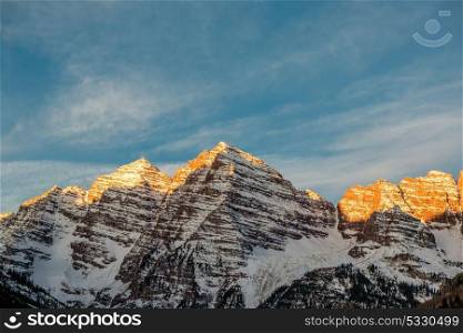 Maroon Bells mountains in snow at sunrise in Colorado, USA.