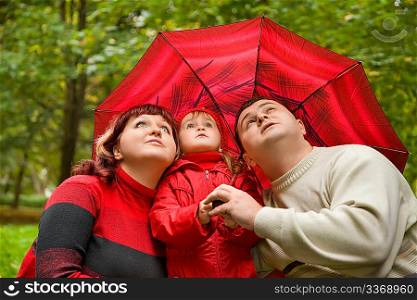 Married couple and little girl with umbrella in park