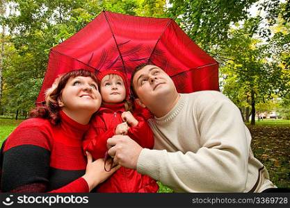Married couple and little girl with umbrella in park