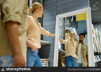 Married couple choosing and buying new mirror together. Furniture store. View from glass reflection. Couple buying mirror together at furniture store