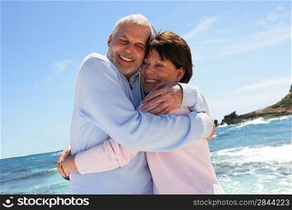 Married couple hugging by the sea