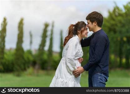 married couple is expecting a baby. man kissing his pregnant wife in the park
