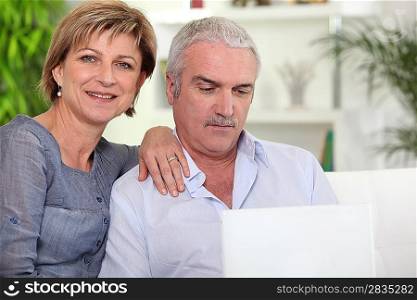 Married couple using a laptop at home