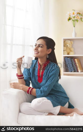 Married Indian woman having coffee in living room