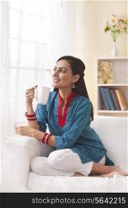 Married Indian woman having coffee in living room