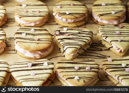 marshmallow sandwiches decorated with chocolate and little pink sugar hearts on the baking tray