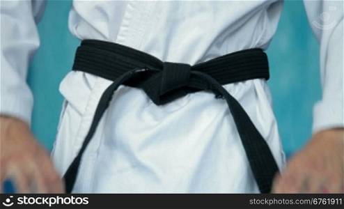 martial arts athlete tying the knot to his black belt