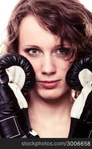 Martial arts or emancipation idea concept. Sport boxer woman in black gloves. Fitness girl training kick boxing showing her power domination. Isolated on white background.