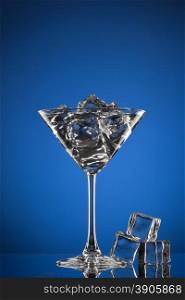 martini glass with ice on blue
