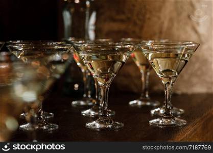 Martini glasses stand on a wooden stand. Martini glasses are on the bar. clean glasses with alcohol. selective focus.. Martini glasses stand on a wooden stand. Martini glasses are on the bar. clean glasses with alcohol. selective focus