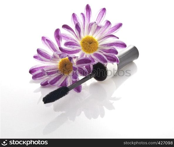 mascara and black flowers on white background