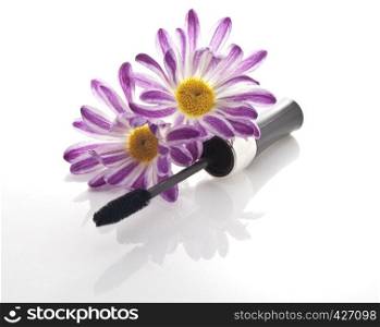 mascara and black flowers on white background