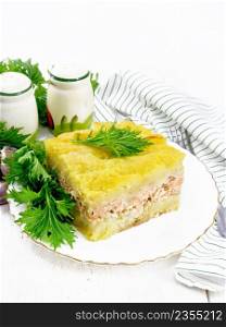 Mashed potato casserole with salmon fillet and lettuce in a plate, napkin, garlic on a wooden board background