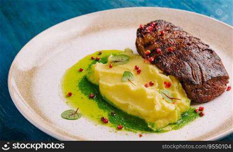 Mashed potatoes and beef steak with pesto sauce