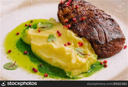 Mashed potatoes and beef steak with pesto sauce