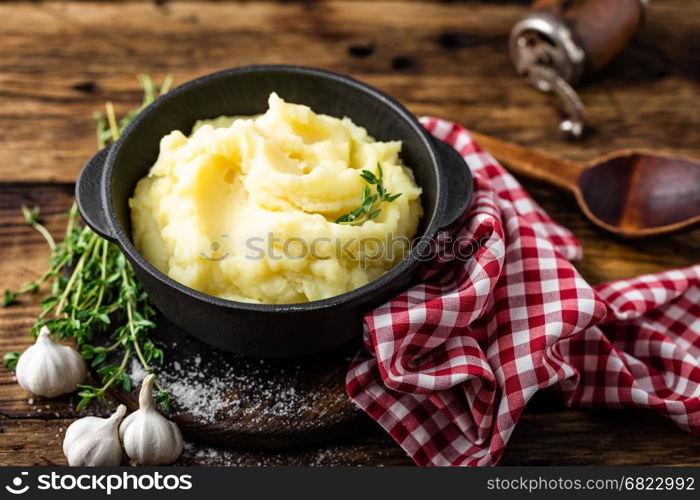 Mashed potatoes, boiled puree in cast iron pot on dark wooden rustic background