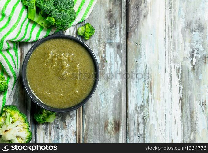Mashed ripe broccoli in a bowl. On a wooden background.. Mashed ripe broccoli in a bowl.