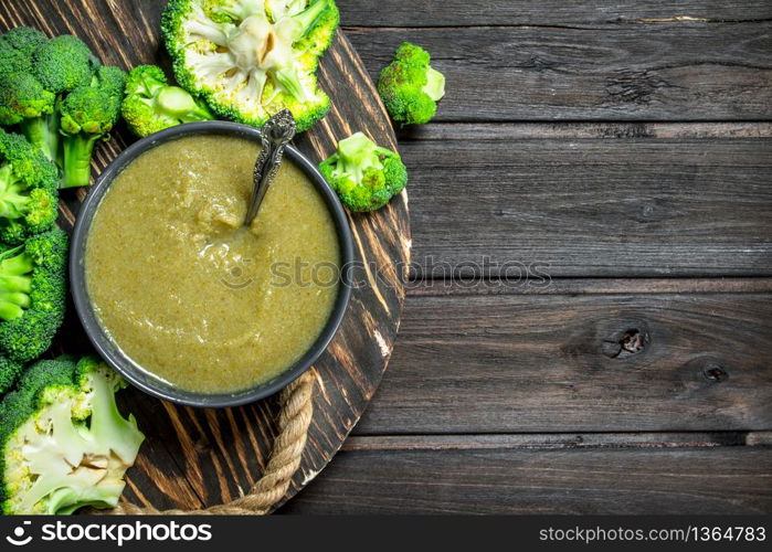 Mashed ripe broccoli in a bowl. On a wooden background.. Mashed ripe broccoli in a bowl