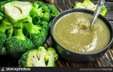 Mashed ripe broccoli in a bowl. On a wooden background.. Mashed ripe broccoli in a bowl