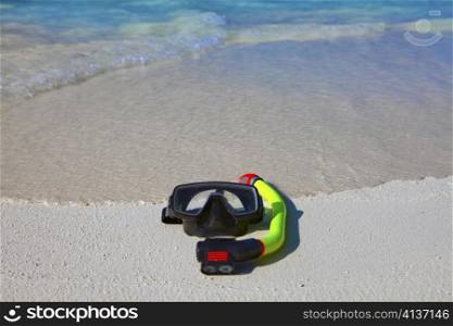 mask and tube lay on sand on background of ocean