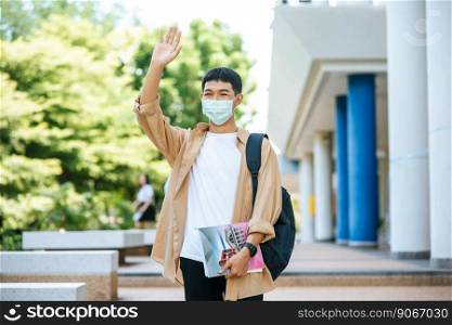 Masked men carry books and backpack on stairs and raise their right hands up.