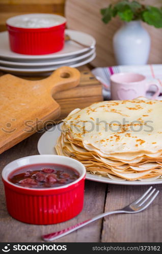 Maslenitsa and pancake week. dish full of russian tradition pancakes with sour cream at saucer