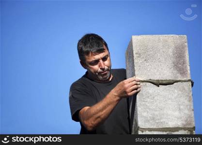 mason erecting a stone block wall