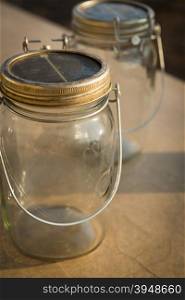 Mason jars with solar power panels powering an LED light under the lid in closeup