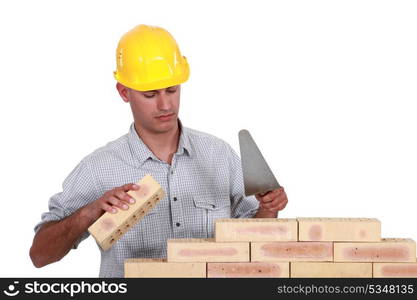 Mason making brick wall, studio shot