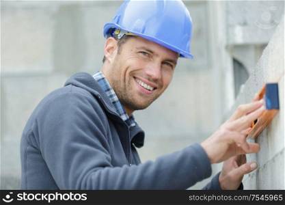 masonry construction worker levels the wall
