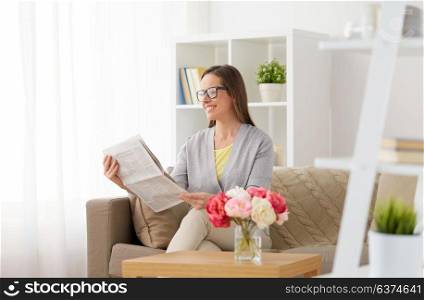 mass media and people concept - happy middle-aged woman reading newspaper at home. happy woman reading newspaper at home