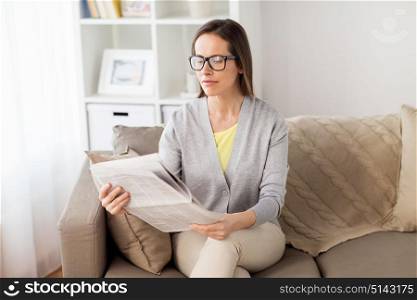 mass media and people concept - happy woman reading newspaper at home. happy woman reading newspaper at home