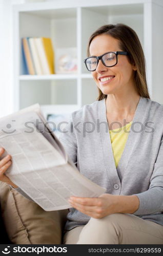 mass media and people concept - woman in glasses reading newspaper at home. woman in glasses reading newspaper at home