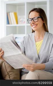 mass media and people concept - woman in glasses reading newspaper at home. woman in glasses reading newspaper at home