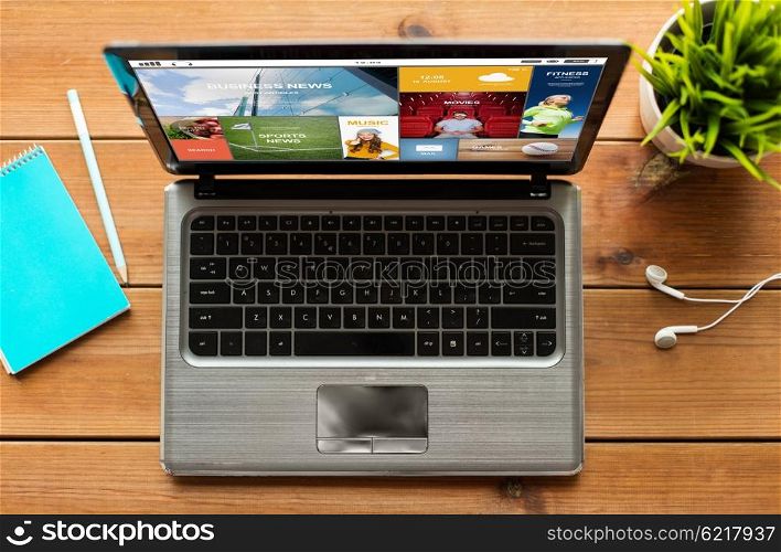 mass media, education, business and technology concept - close up of laptop computer with internet news application on screen on wooden table