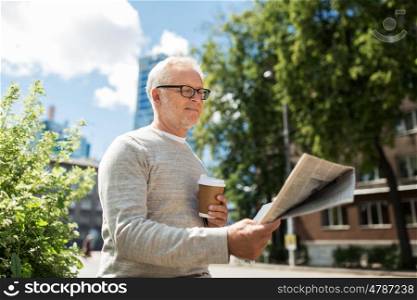 mass media, news and people concept - senior man reading newspaper and drinking coffee in city