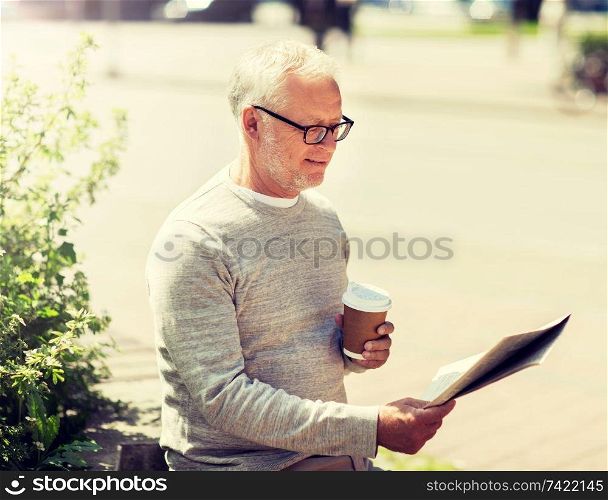 mass media, news and people concept - senior man reading newspaper and drinking coffee in city. senior man reading newspaper and drinking coffee