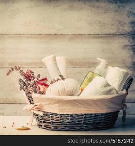 Massage or sauna setting in basket with herbal compress balls , fresh herbs and cosmetic products on wooden background, front view. Healthy Lifestyle or Spa and wellness concept