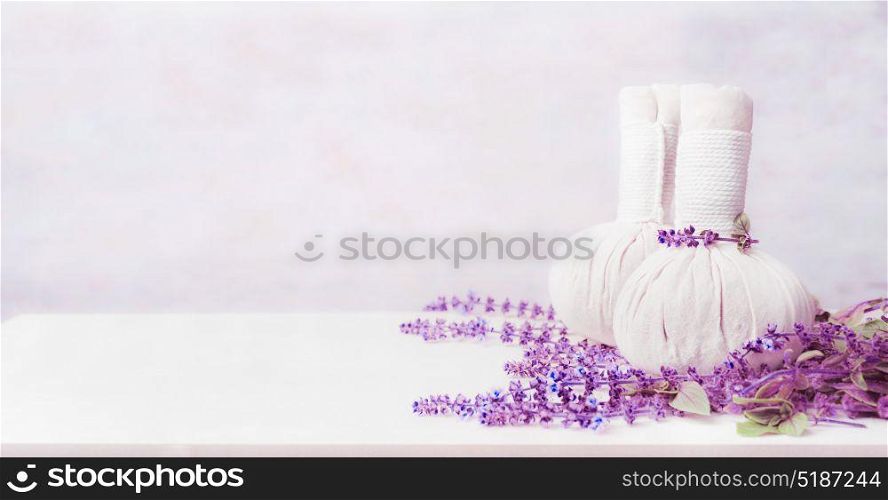 Massage setting with two herbal compress balls and fresh herbs on white wooden background, front view, banner. Healthy Lifestyle or Spa and wellness concept