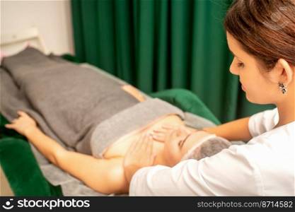Massaging female breast, and shoulder. Beautician doing chest and shoulders massage of the young beautiful caucasian woman in beauty spa salon. Massaging female breast, and shoulder. Beautician doing chest and shoulders massage of the young beautiful caucasian woman in beauty spa salon.