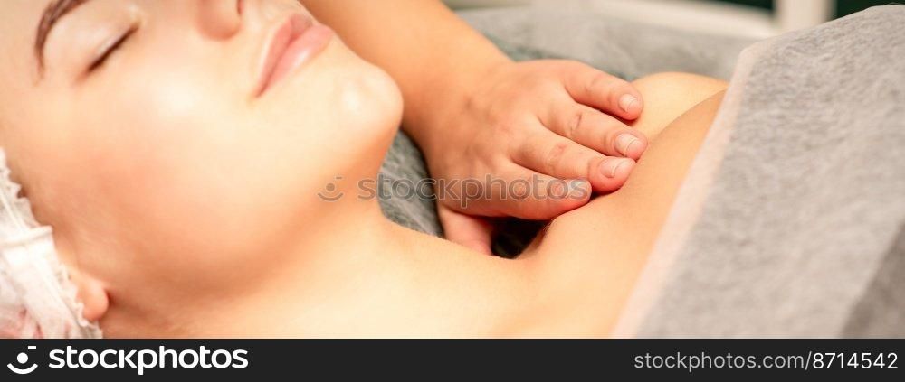 Massaging female breast, and shoulder. Young beautiful caucasian woman with closed eyes receiving chest and shoulders massage in beauty spa salon. Massaging female breast, and shoulder. Young beautiful caucasian woman with closed eyes receiving chest and shoulders massage in beauty spa salon.