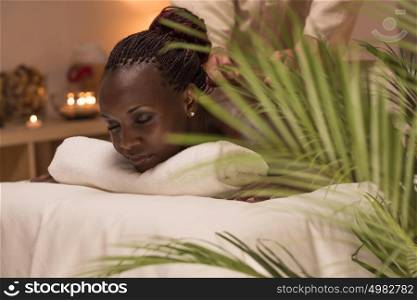 Masseur doing massage to african woman body in the spa salon. Beauty treatment concept.