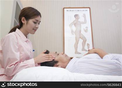 Masseuse Giving Chinese Traditional Medical Facial Massage