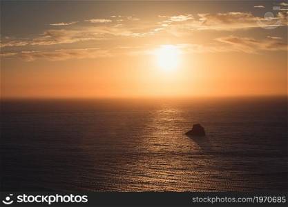 Massive sunset over the ocean with a rock in it